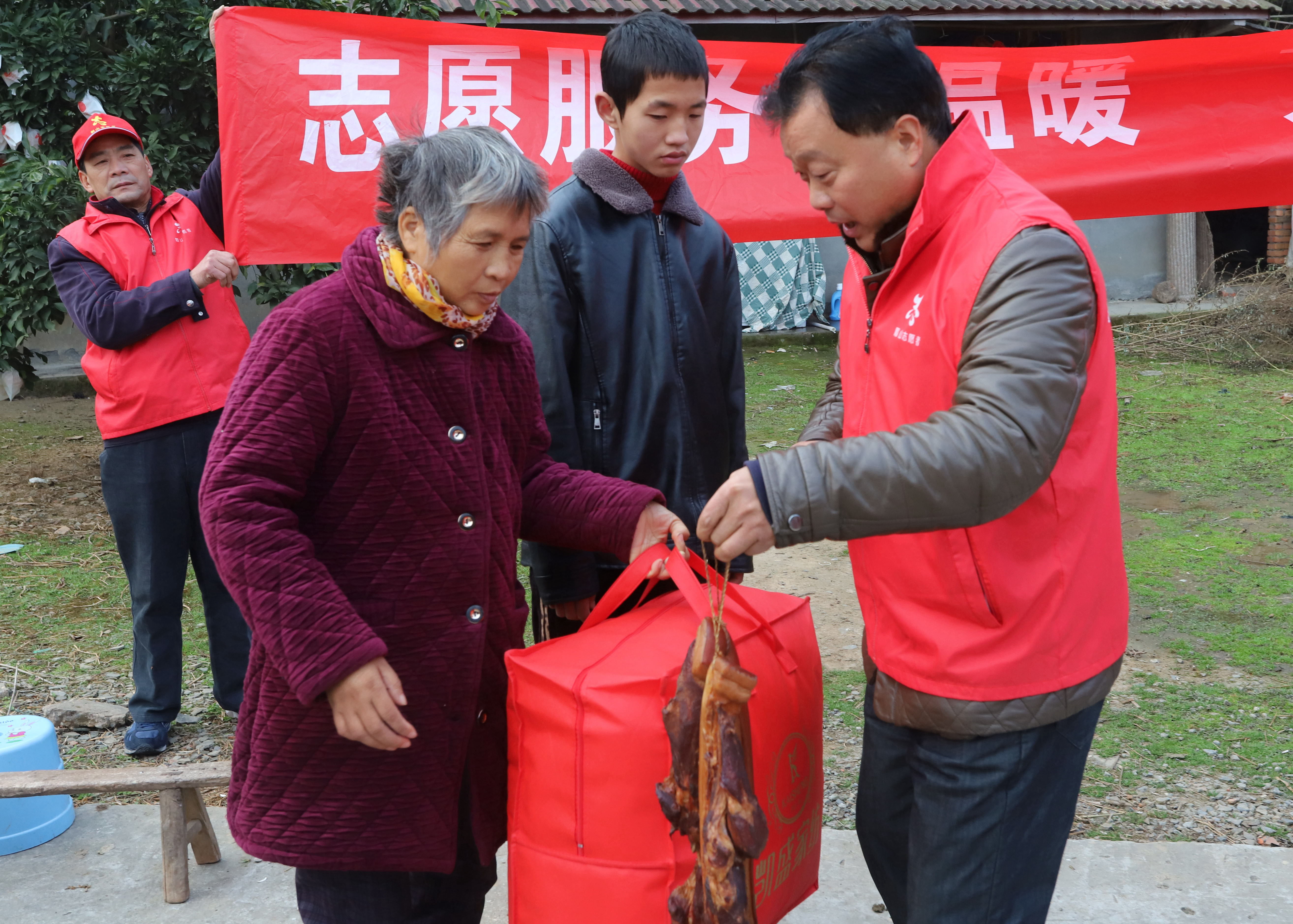 ２志愿者在為劉淑仙，張濤母子送被子和臘肉。.JPG