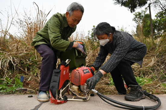 志愿者正在雙橋鎮(zhèn)豆芽村為割草機(jī)添加燃油.jpg